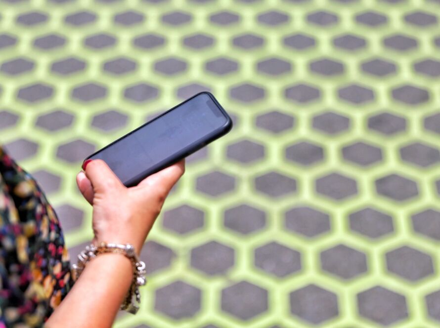 Young woman holding phone against a patterned yellow ground